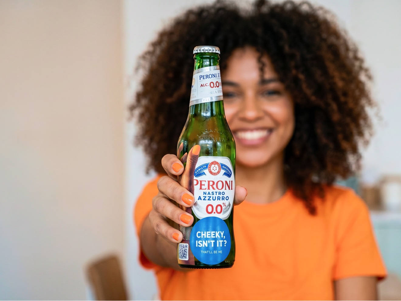 A visitor smiling with a stickered Peroni bottle