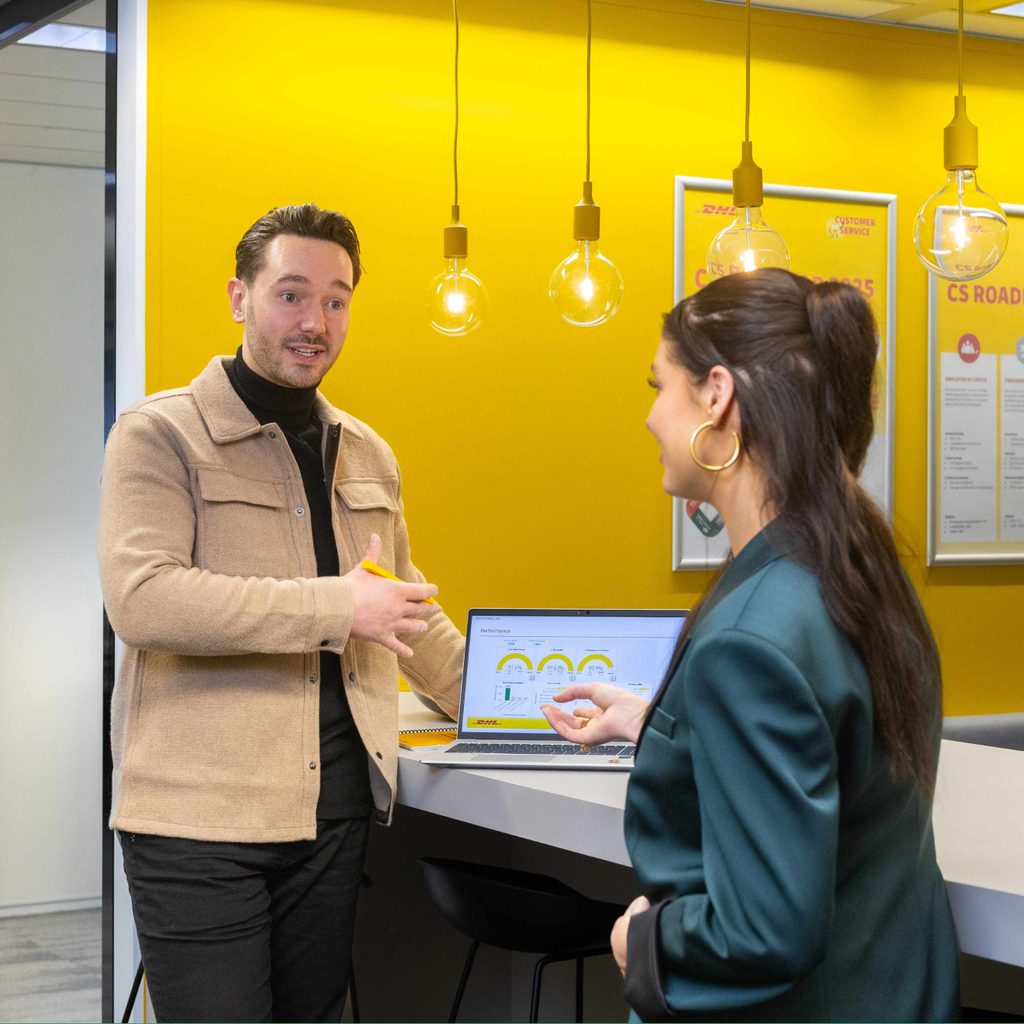 Two DHL colleagues talking over a laptop in a DHL office