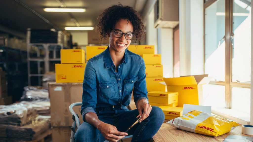 A small business owner at her packing table, surrounded by DHL parcels